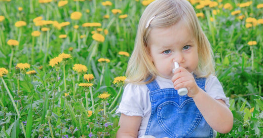 A young girl with seasonal allergies sneezing in a field of yellow dandelions.