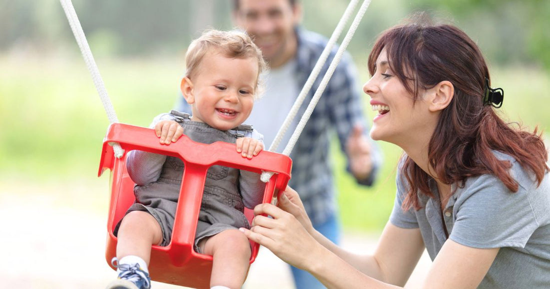 Father, mother, and son having fun together on swings at the playground.