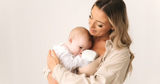 Mom carrying baby while using the KeaBabies Pulse Breast Pump