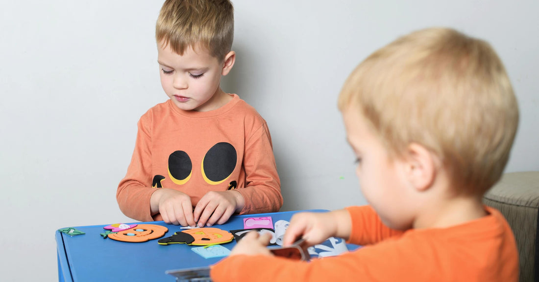 Toddler boys having fun making DIY Halloween crafts and enjoying creative fall activities together