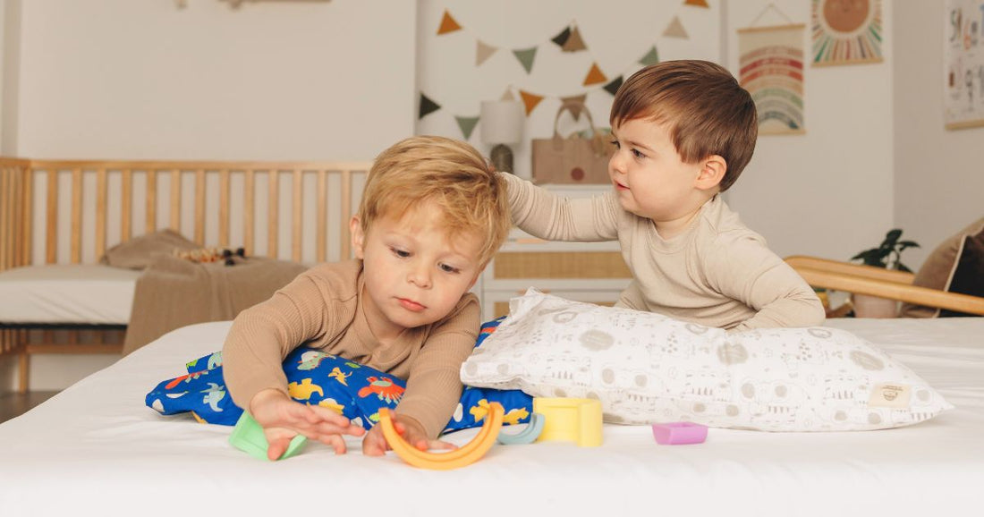 Two toddler boys playing on a bed, creating a cozy and snuggly atmosphere