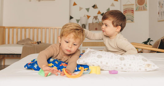 Two toddler boys playing on a bed, creating a cozy and snuggly atmosphere