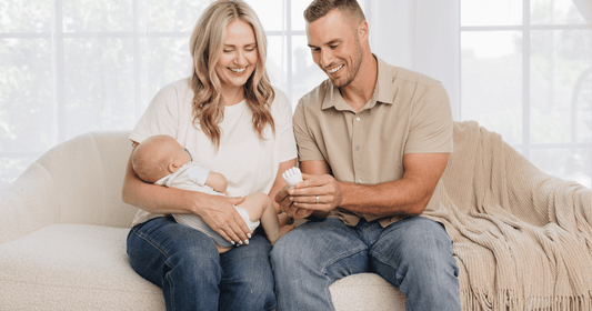 Couple sitting on the couch with sleeping baby and a finished hand cast.