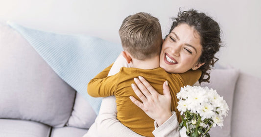 Mom joyfully hugging her toddler as they gift her a bouquet of flowers – heartwarming parent-child moment.