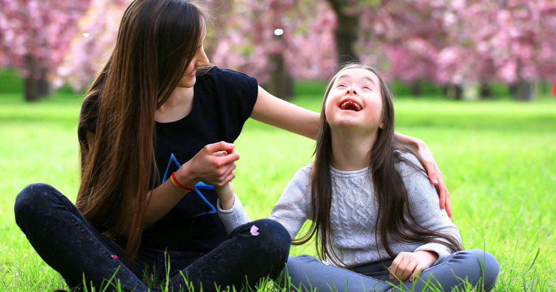 Smiling child with Down syndrome enjoying a sunny day at a blossom-filled park, sharing a joyful moment with their mom.