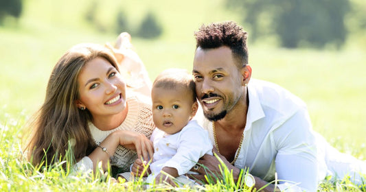 Multiracial parents spending quality time with their mixed-race baby in the park on a sunny day.