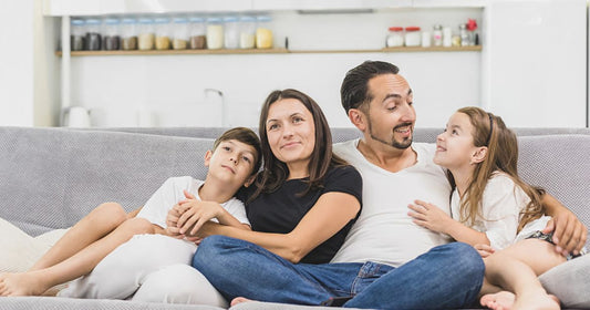 Family sitting on sofa smiling at camera on modern apartment.