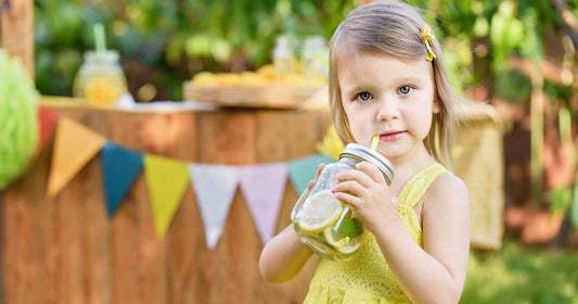 Toddler sipping on her refreshing lemon and mint-infused water—staying cool and hydrated the healthy way.