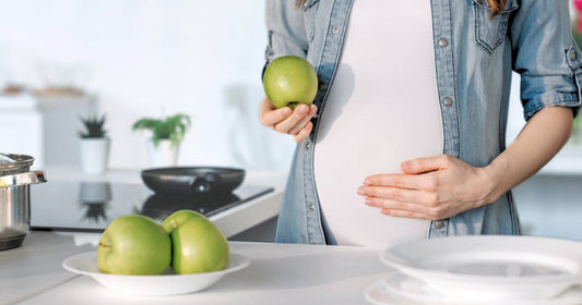Pregnant woman holding a fresh apple for healthy pregnancy diet.